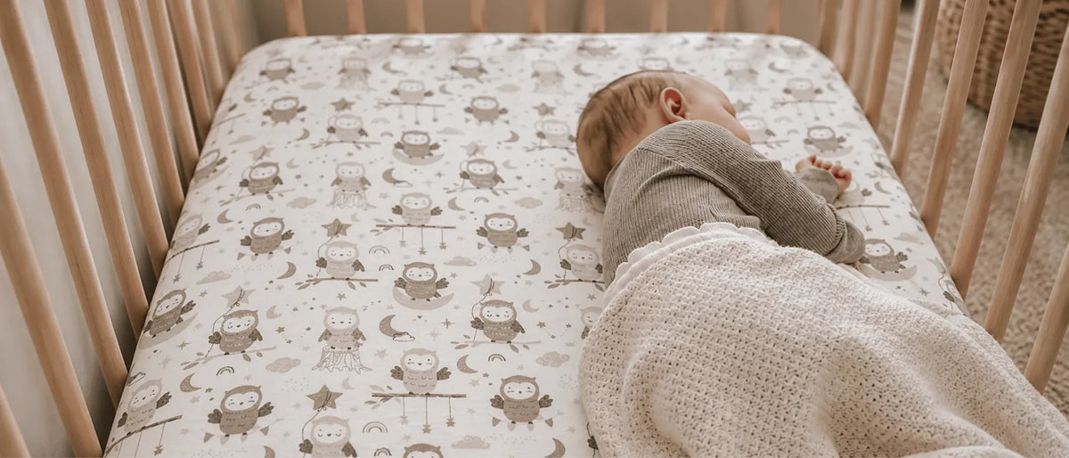An image showing a baby sleeping on a fitted sheet