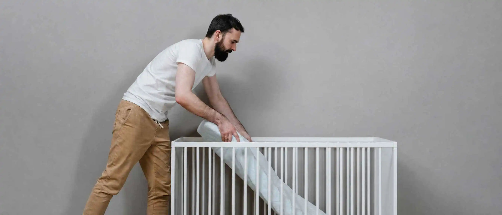 An image of a parent putting a mattress in the crib