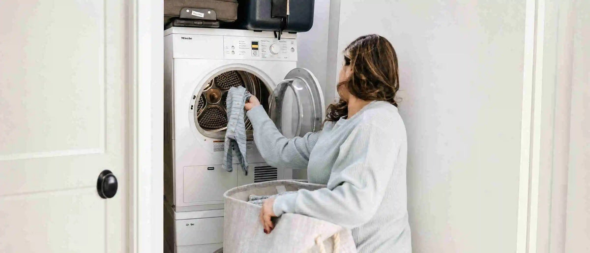 A mother putting baby clothes in the washing machine
