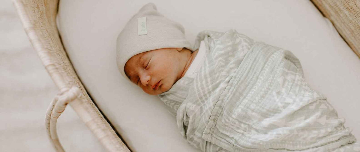 A newly born baby lying in a bassinet