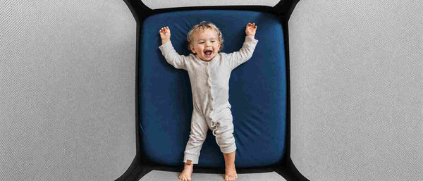 A baby lying on a cotton microplastics free crib sheet
