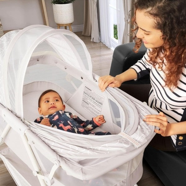 A mother tucking her baby into a Dream On Me bassinet