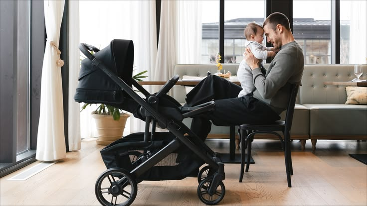A father holding his baby beside an UPPAbaby stroller