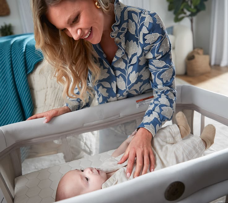 A mother smiling at her baby in a Maxi-Cosi Calao travel play yard