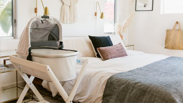 A mother settling her baby into an UPPAbaby bassinet on its stand
