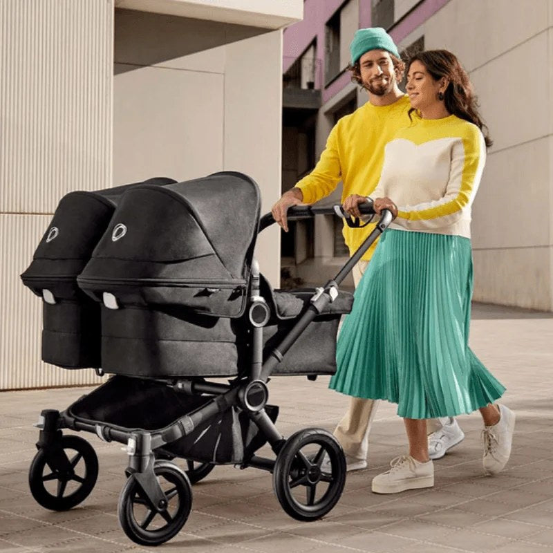 Parents walking with a Bugaboo Donkey stroller with two bassinets