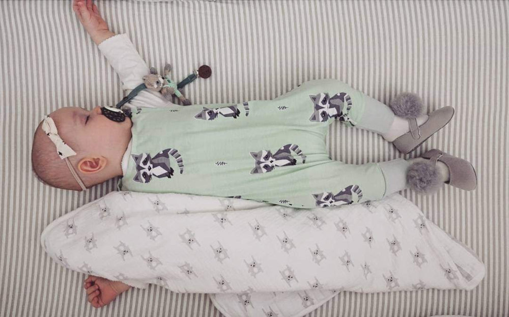 A baby resting on a Joey + Joan jersey knit cotton bassinet sheet