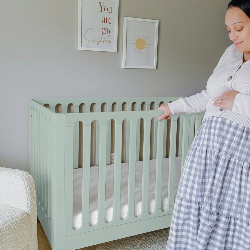 Expecting mother beside a Newton crib