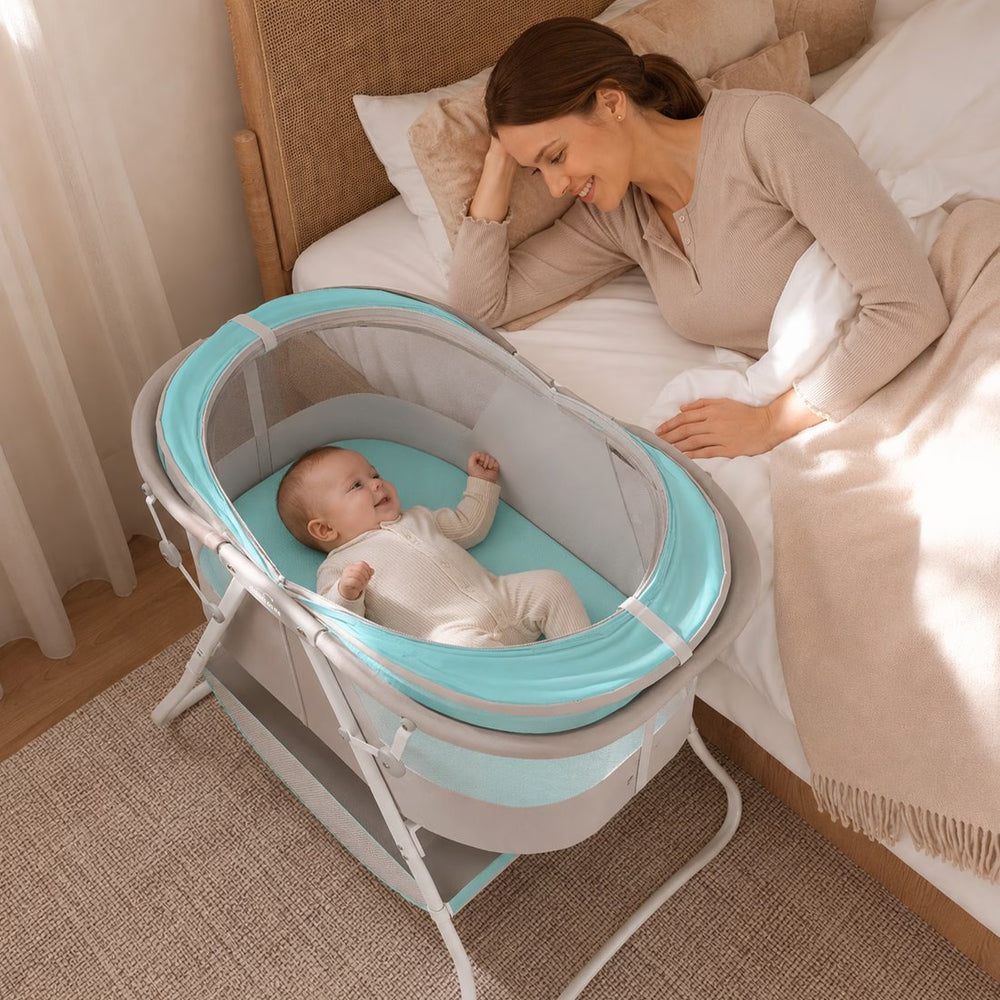 A mother smiling at her baby in a Dream On Me bassinet beside the bed