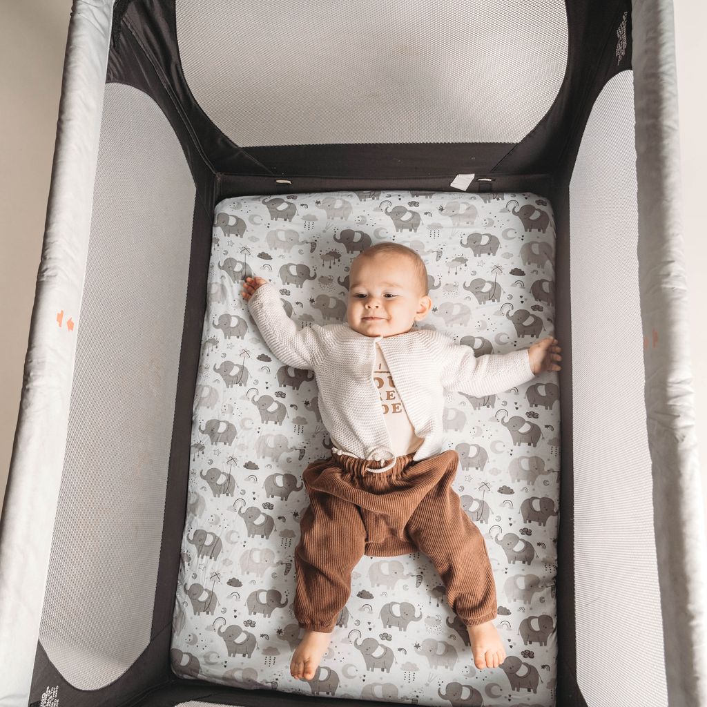 Baby in a playard on a Joey + Joan fitted sheet