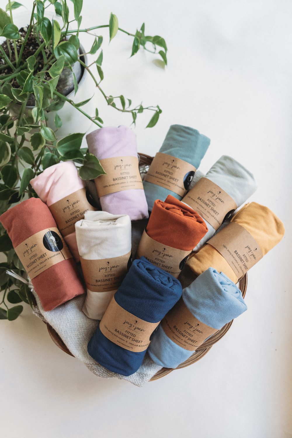 Basket of Joey + Joan fitted bassinet sheets in many colors
