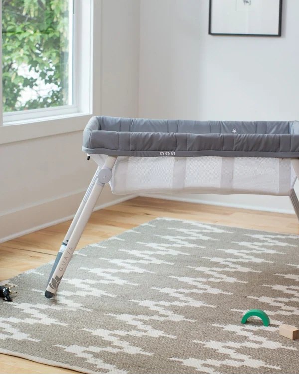Guava Lotus Travel Bassinet set up beside a window