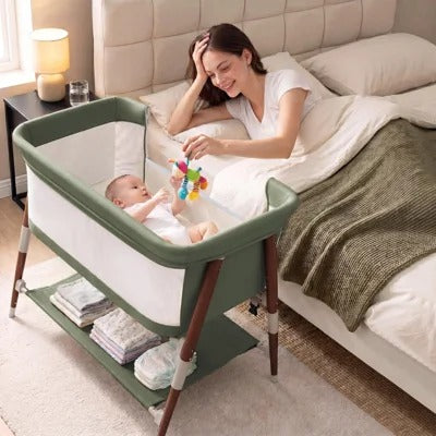 A mother smiling at her baby in a bedside bassinet